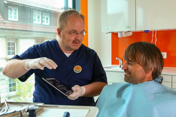 Patient sitzt auf Zahnarztstuhl der Fairpreispraxis