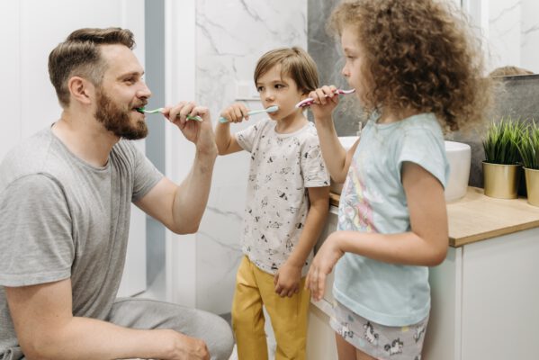 Vater mit zwei Kindern beim Zähneputzen